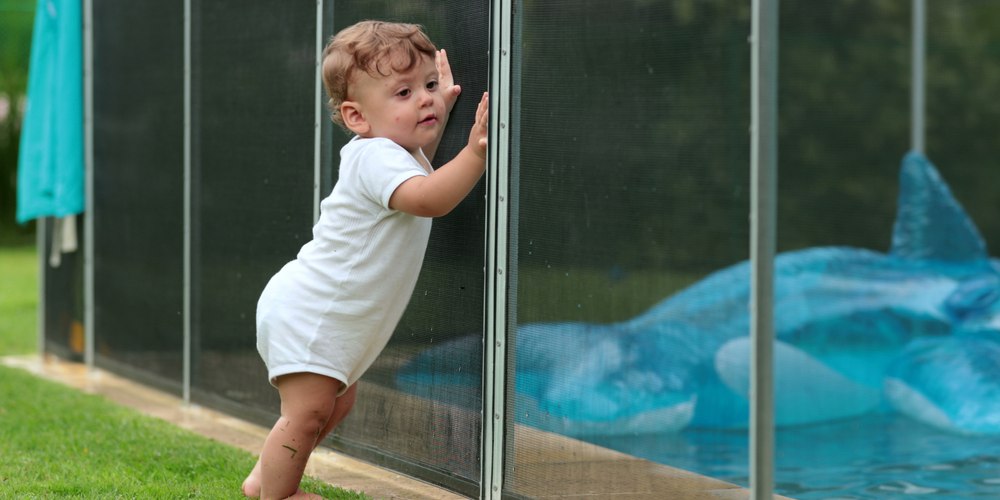 toddler leaning on a mesh pool fence