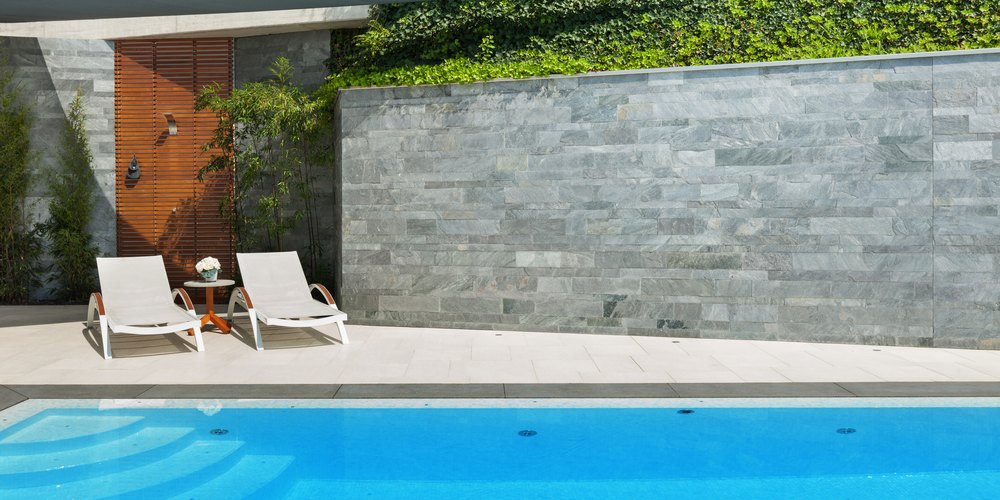 stone retaining wall in front of a pool