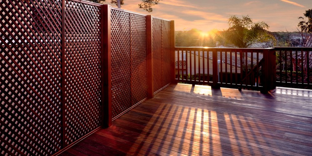 sunset over a deck with trellis and a wooden fence