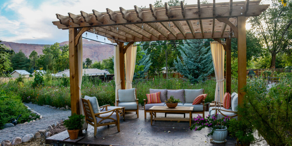 backyard pergola with curtains on the sides and seating underneath