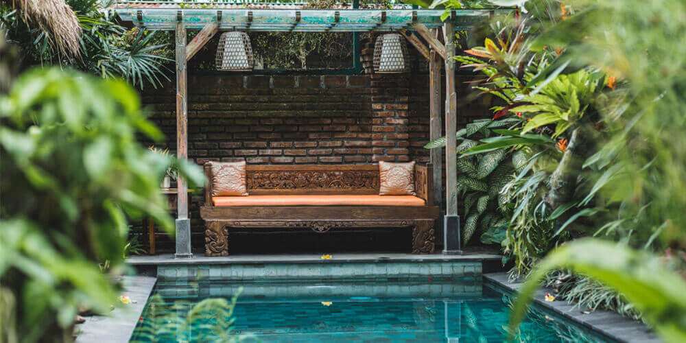 backyard pool in a small space with a couch and a lot of plant life