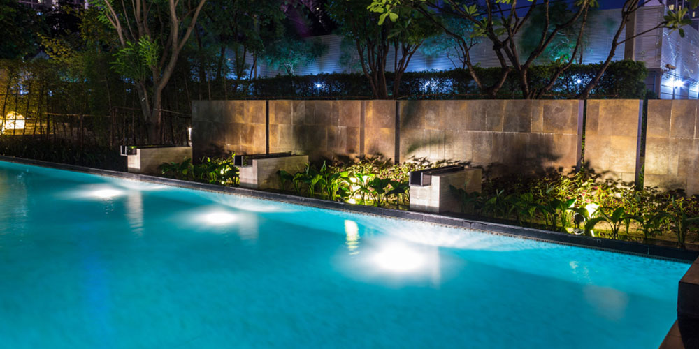 pool at night with garden and fence lit up with ground lights
