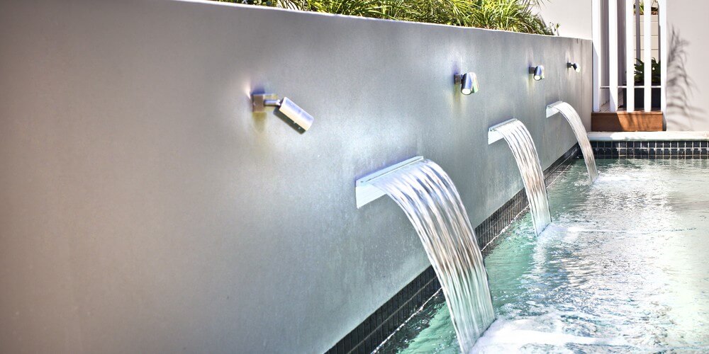 pool fountains out of a wall with spot lights on them