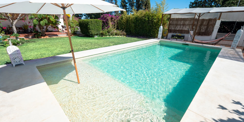 tanning ledge in rectangular pool with umbrella incorporated into it