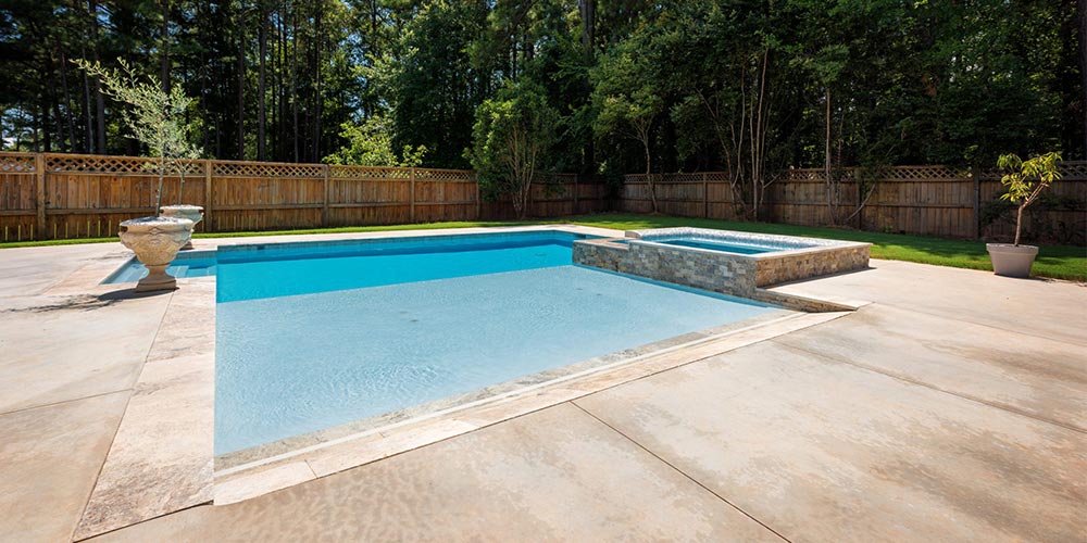 beach entry pool with concrete decking in a backyard