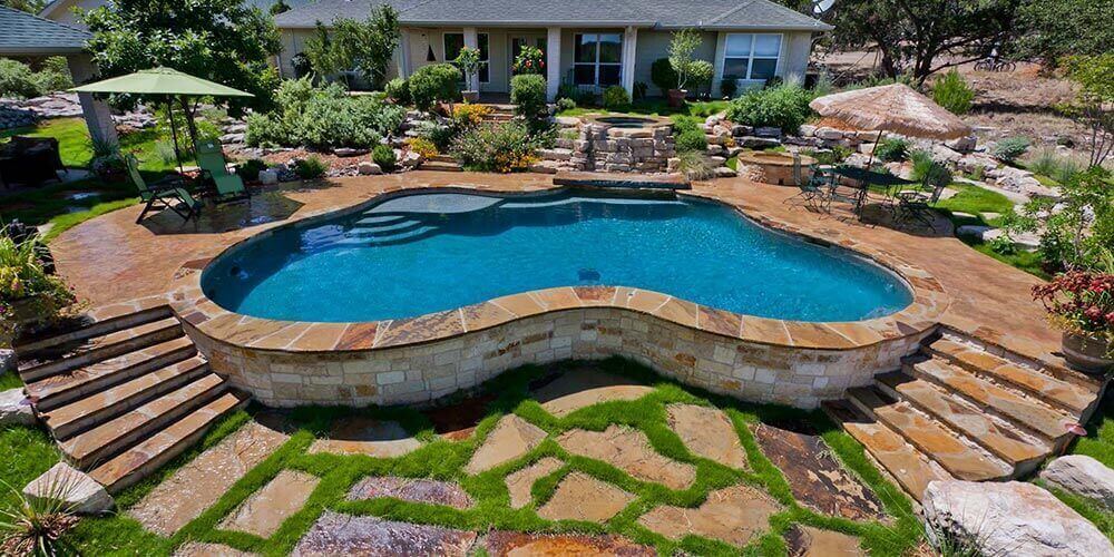 large backyard with a pool with a stone garden all over the property