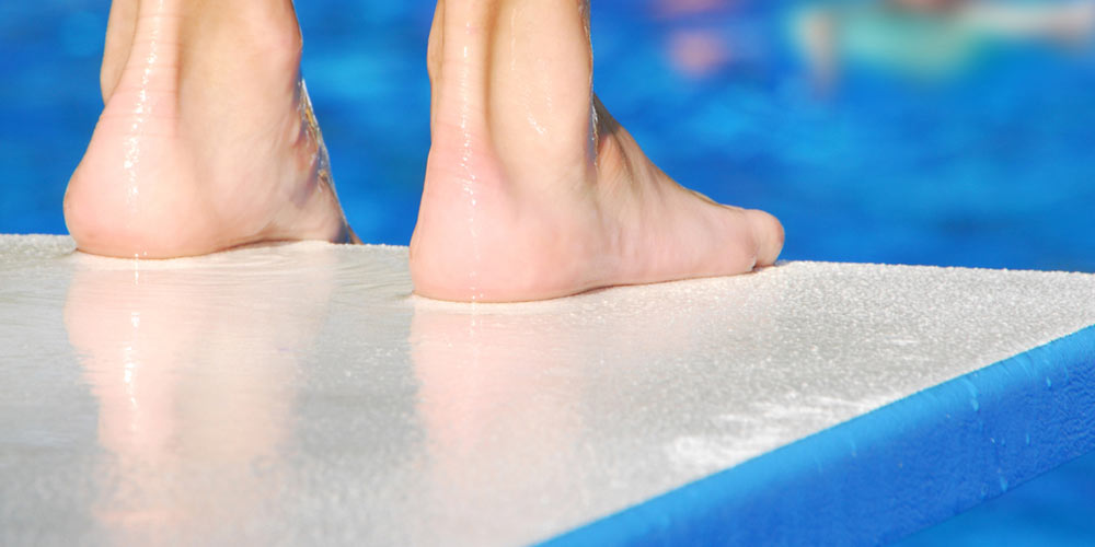 pair of feet at edge of diving board, waiting for pool to clear before jumping