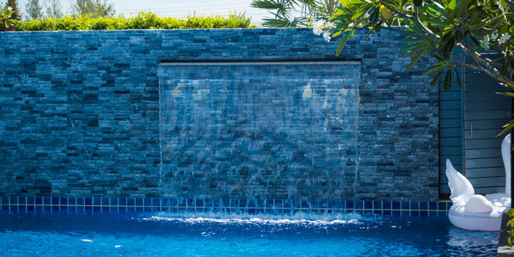 water feature coming out of a wall and into a swimming pool