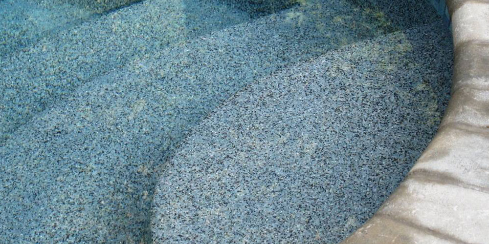close up of steps of a pool that have an aggregate finish