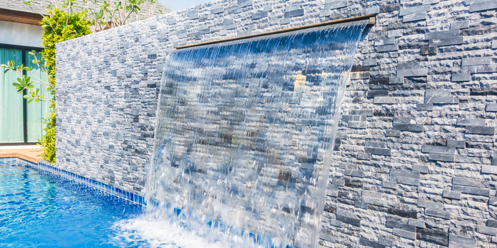 water fountain cascade from wall into swimming pool
