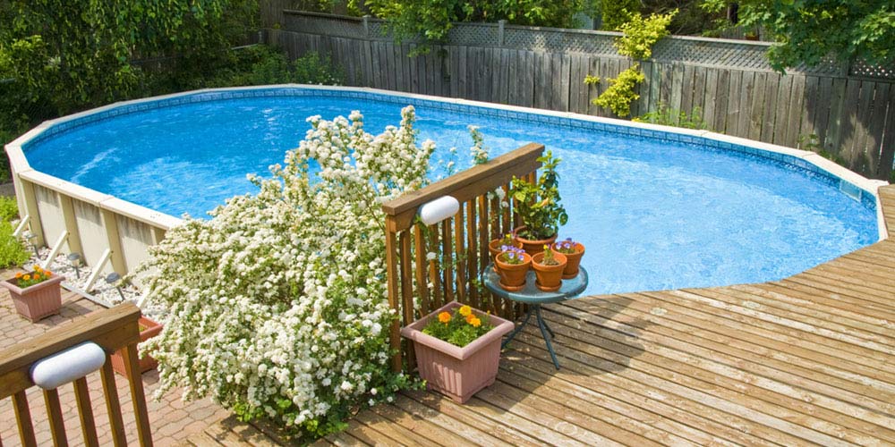 backyard above ground pool with decking around half of it.