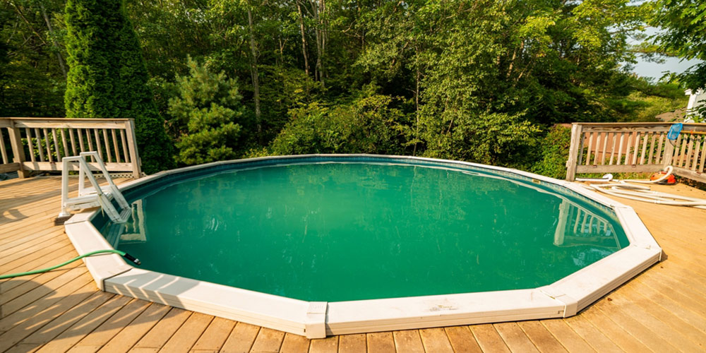 small round swimming pool with a deck backing onto trees