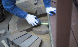 man measuring and marking bricks for a decorative two tone paver pattern