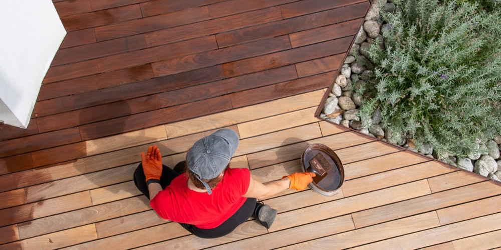 top down view of someone applying stain to a deck