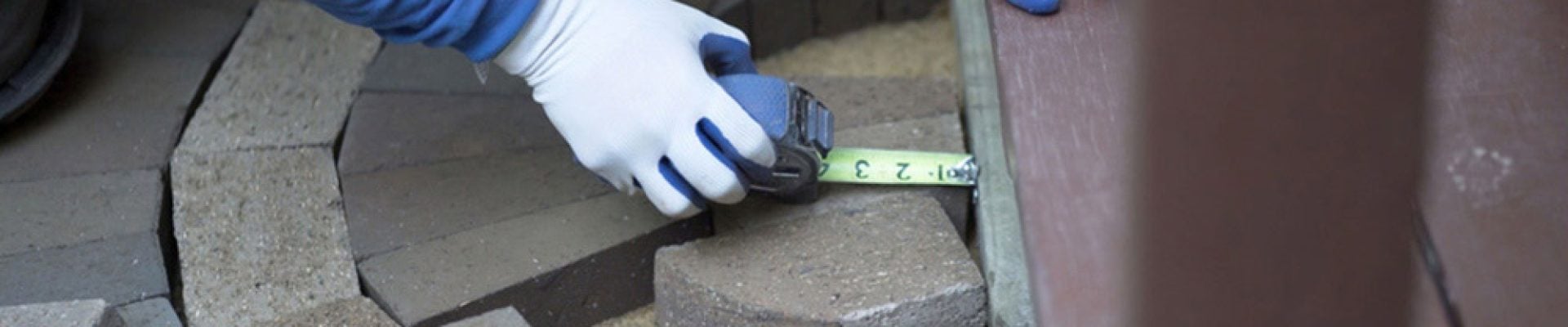 man measuring and marking bricks for a decorative two tone paver pattern
