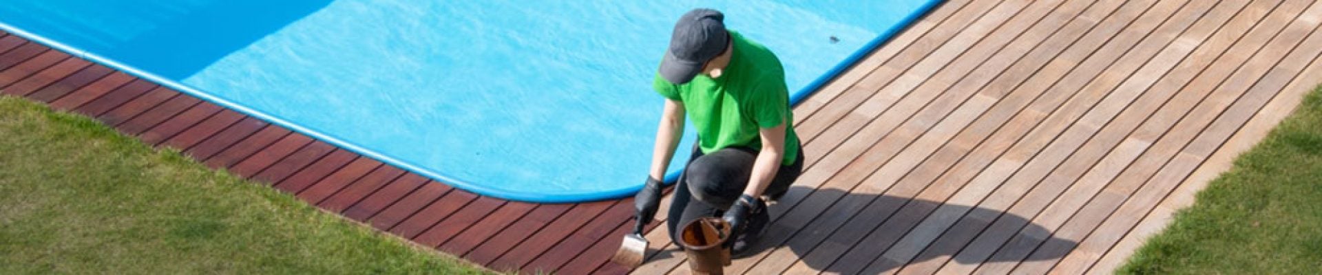 person applying refreshing coat to poolside wood decking